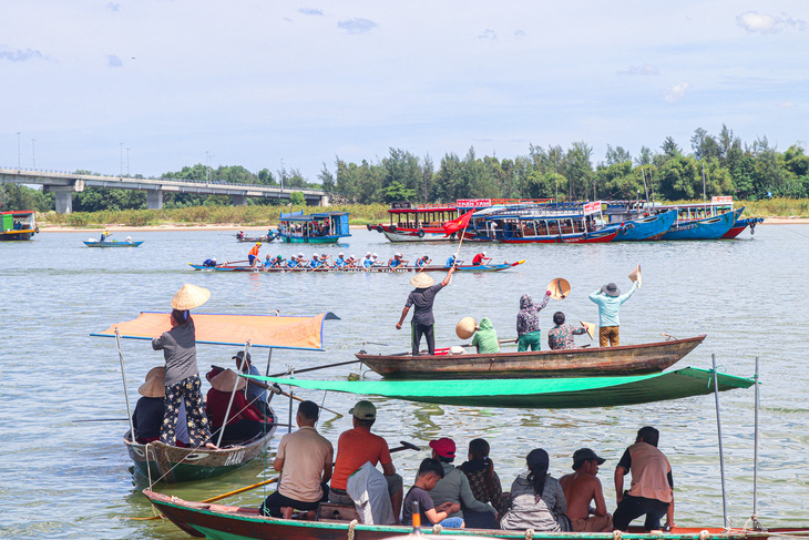 Người dân đứng trên thuyền cổ vũ các đội đua - Ảnh: THANH NGUYÊN