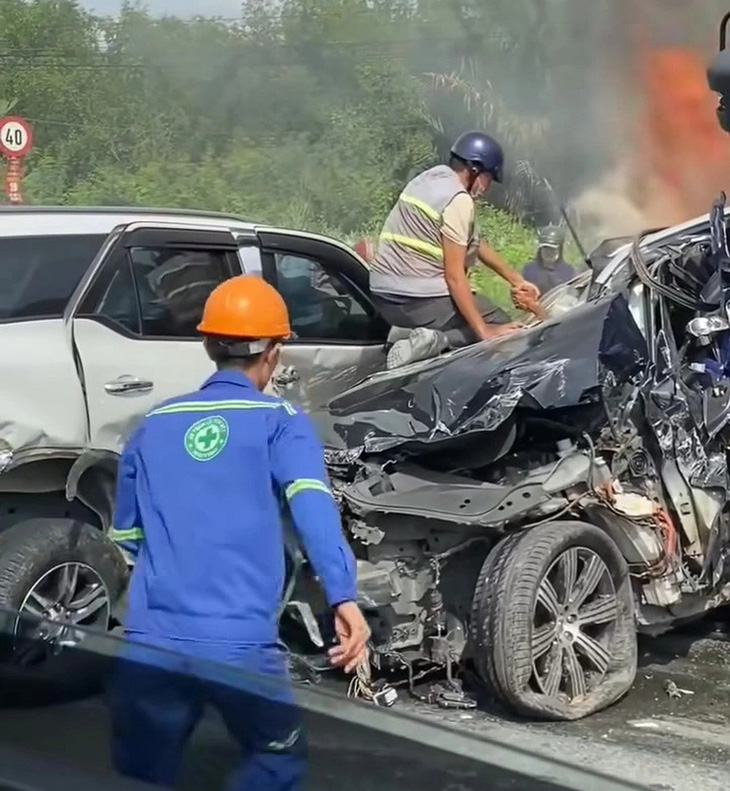 Nam công nhân nắm tay tài xế kéo ra khỏi xe bị bẹp dúm, nát bét - Ảnh: Cắt từ video