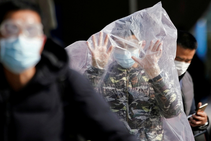 Một hành khách đeo khẩu trang và trùm thêm một túi nhựa, đi bên ngoài nhà ga đường sắt Thượng Hải, ngày 9 tháng 2 năm 2020, vào lúc virus corona ở Trung Quốc đã làm nhiều người chết hơn cả hồi dịch hô hấp cấp tinh SARS 2002-2003. Hình của Aly Song (Reuters).