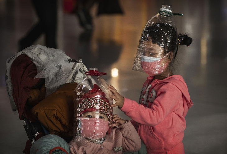 Trẻ em Trung Quốc đeo vỏ chai nhựa tự chế như mặt nạ bảo vệ tạm thời, trong khi chờ làm thủ tục lên máy bay ở sân bay Bắc Kinh, ngày 30 tháng 1 năm 2020. Hình của Kevin Frayer (Getty Images).