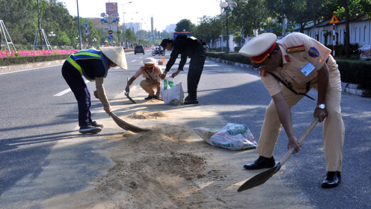 Cảnh sát giao thông phụ quét dọn cát giúp công nhân