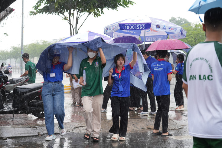 Sĩ tử có mặt ở điểm thi Trường THPT An Lạc rất sớm vì sợ mưa lớn ngập đường. Các bạn sinh viên hỗ trợ vào phòng thi- Ảnh: VŨ