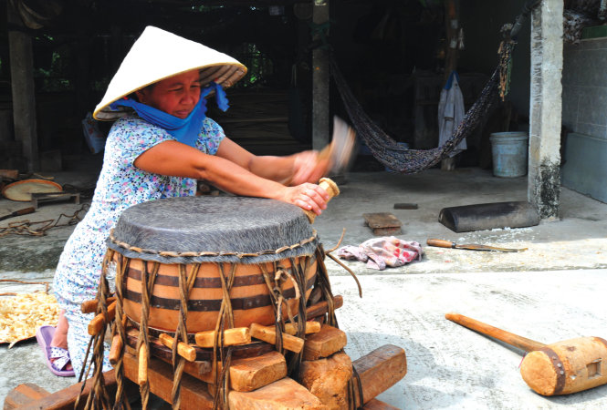 Chị Hai Thâu dùng búa dăm xung quanh để da mặt trống được căng