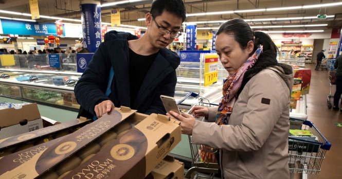 Khách hàng kiểm tra mã vạch trên một kiện hàng đựng trái kiwi ở một siêu thị Trung Quốc  -The New York Times