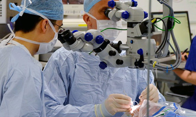 Giáo sư Robert MacLaren (phải) thực hiện phẫu thuật cấy gen khỏe mạnh vào mắt một bệnh nhân   -University of Oxford