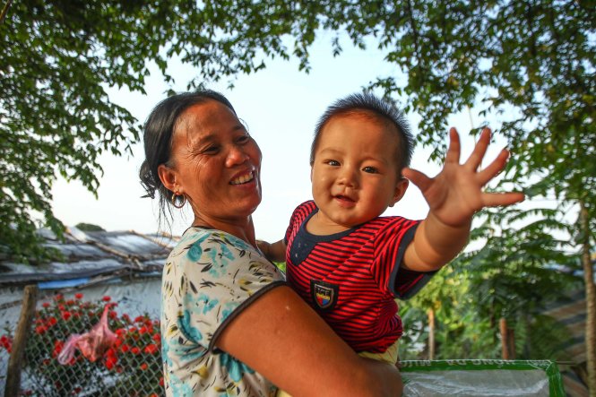 Bà Lê Thị Hiền nô đùa với cháu là bé Hoàng Ngọc Huy, 8 tháng tuổi. Do sức khỏe đã xuống nên bà chủ yếu ở nhà trông cháu, việc rong ruổi bán hàng giờ cũng không thường xuyên