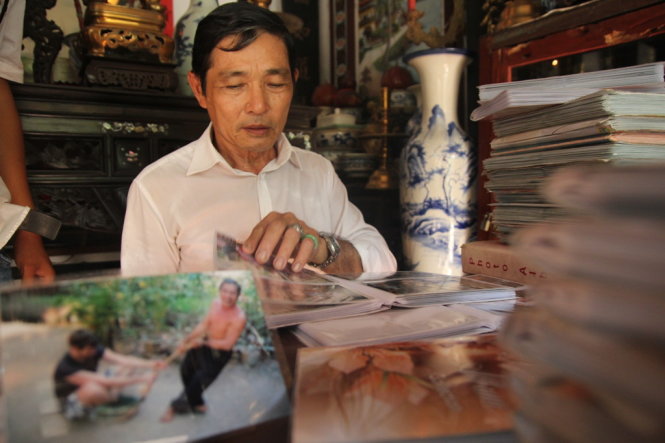 Ông Trần Công Khánh với chồng ảnh chụp du khách từng ghé thăm vườn nhà ông-MẬU TRƯỜNG