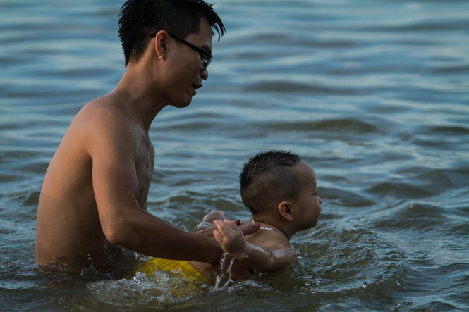 Một em bé 3 tuổi được bố giữ tập bơi trong tình trạng không có áo phao bảo vệ