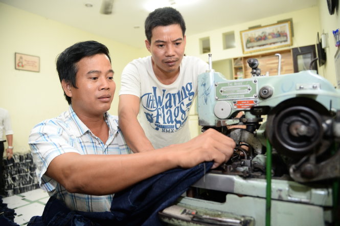 Anh Trần Xuân Bảo Thiệp, chủ cơ sở sản xuất may mặc Đăng Khoa, Q.Tân Bình (đứng), hướng dẫn công nhân may -Tự Trung