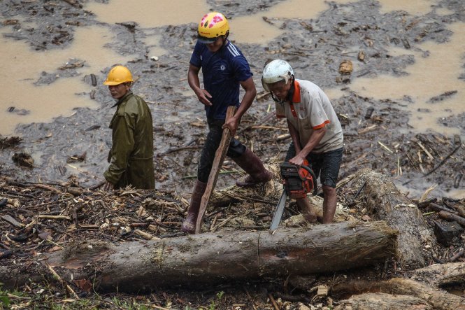 Hai người đàn ông đang cố gắng xẻ một khúc gỗ mới vớt lên được từ lòng suối Nậm Kim (Mù Cang Chải).-Ảnh: Nguyễn Khánh