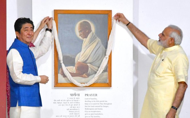 Ông Abe (trái) rạng rỡ trong bộ quốc phục Ấn Độ bên cạnh chủ nhà Modi trước bức tranh nhà tranh đấu vĩ đại cho độc lập của Ấn Độ Mohandas Gandhi ở thành phố Ahmedabad, quê nhà của ông Modi. -Ảnh: Kyodo News