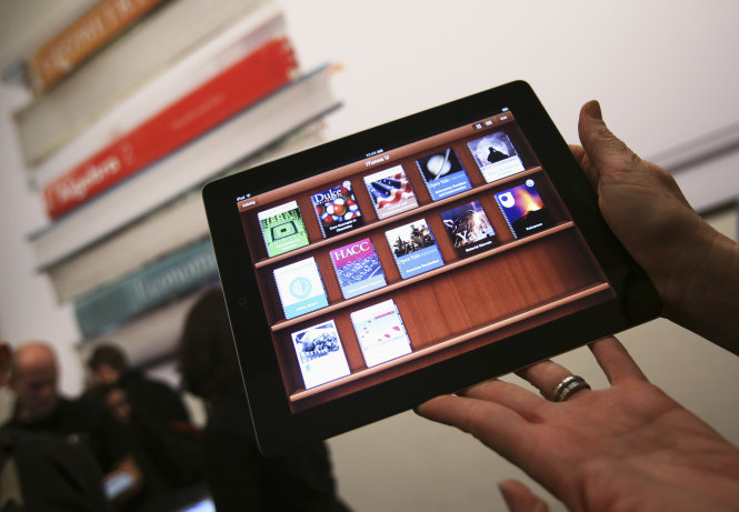 A woman holds up an iPad with the iTunes U app after a news conference introducing a digital textbook service in New York in this January 19, 2012, file photo. The U.S. Justice Department has warned Apple and five major U.S. publishers that it plans to sue them, accusing them of colluding to raise the prices of electronic books, a person familiar with the probe said on March 8, 2012.      REUTERS/Shannon Stapleton/Files (UNITED STATES - Tags: SOCIETY EDUCATION SCIENCE TECHNOLOGY BUSINESS) - RTR2Z1Q3