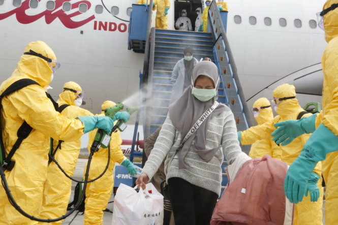 Nhân viên y tế phun thuốc khử trùng cho những công dân Indonesia được di tản khỏi Vũ Hán trở về nước. Họ sẽ được cách ly ở căn cứ quân đội trên đảo Natuna. Ảnh: REUTERS