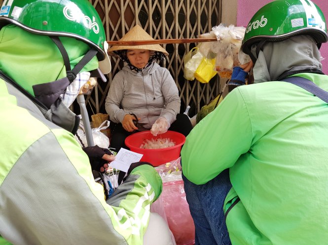 Gánh hàng rong của một phụ nữ bán bánh tráng trộn tại quận Phú Nhuận bị “bao vây” bởi các shipper công nghệ.  Ảnh: NGỌC HIỂN