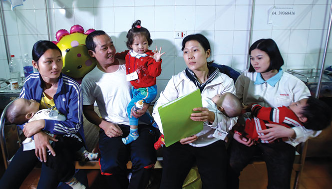Nguyễn Thị Hạnh (được mẹ bế, thứ hai từ phải sang) có cha cũng bị hở môi. Em là một trong số những trẻ em được phẫu thuật đợt này