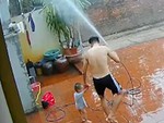 Bố cầm vòi phun nước làm mưa nhân tạo chơi cùng con