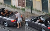 Người đàn ông loay hoay tìm cách đóng mui trần BMW dưới trời mưa