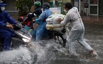 TP.HCM mưa trắng trời, nhân viên trực chốt đẩy xe dân qua chỗ ngập