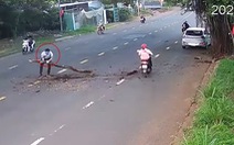 Tài xế dừng ôtô để ôm khúc gỗ vào lề đường tránh gây tai nạn