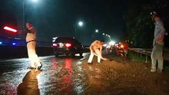 Cảnh sát giao thông và người dân dọn đất đá trên quốc lộ 1 sau mưa lớn