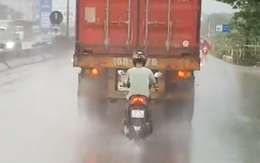 Chạy xe máy bám đuôi container để trú mưa