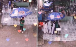 Chú bảo vệ cầm ô che mưa cho học sinh sang căn-tin