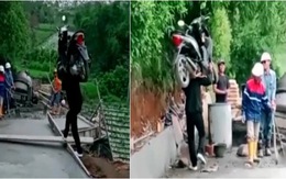 Chàng trai vác xe máy băng qua đường vừa đổ bê tông
