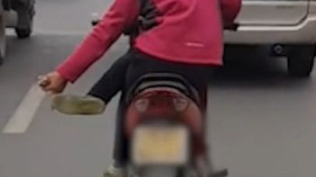 Nữ quái xế ngồi gác chéo chân lái xe máy