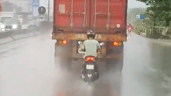 Chạy xe máy bám đuôi container để trú mưa