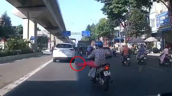 Người phụ nữ đi xe máy vẩy chân xi nhan qua đường