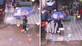 Chú bảo vệ cầm ô che mưa cho học sinh sang căn-tin