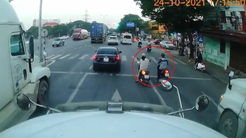 2 cô gái dừng xe máy giữa đường chờ đèn đỏ để rẽ trái