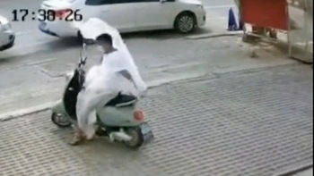 Chàng trai bối rối khi bị áo mưa bay trên đường quấn vào người