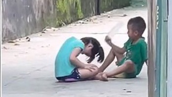 2 đứa trẻ chơi oẳn tù tì, ai thua bị gõ chai nhựa vào đầu
