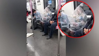 Nữ hành khách trùm kín túi ni lông ngồi ăn trên tàu điện