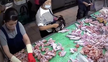 A woman stealing chicken thighs at the market was caught red-handed