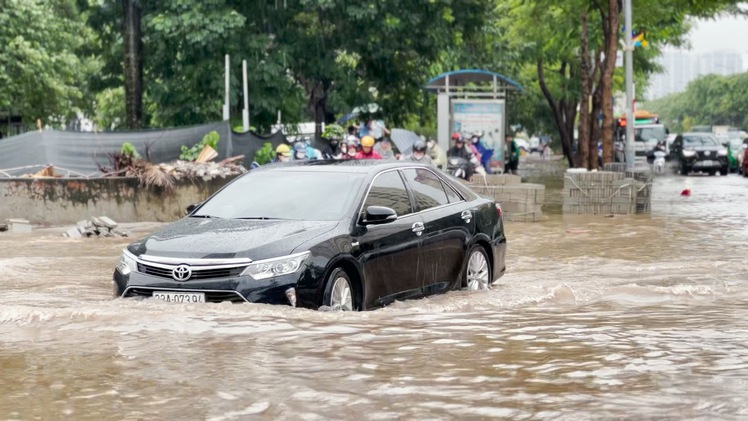 Đưa xe máy lên lề dắt bộ do mưa lớn, đường ngập lênh láng ở Hà Nội