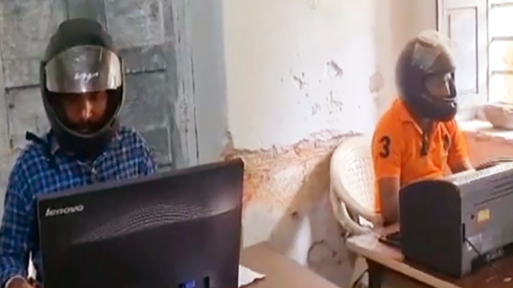 Công chức ở Ấn Độ ngồi làm việc trong văn phòng phải đội mũ bảo hiểm